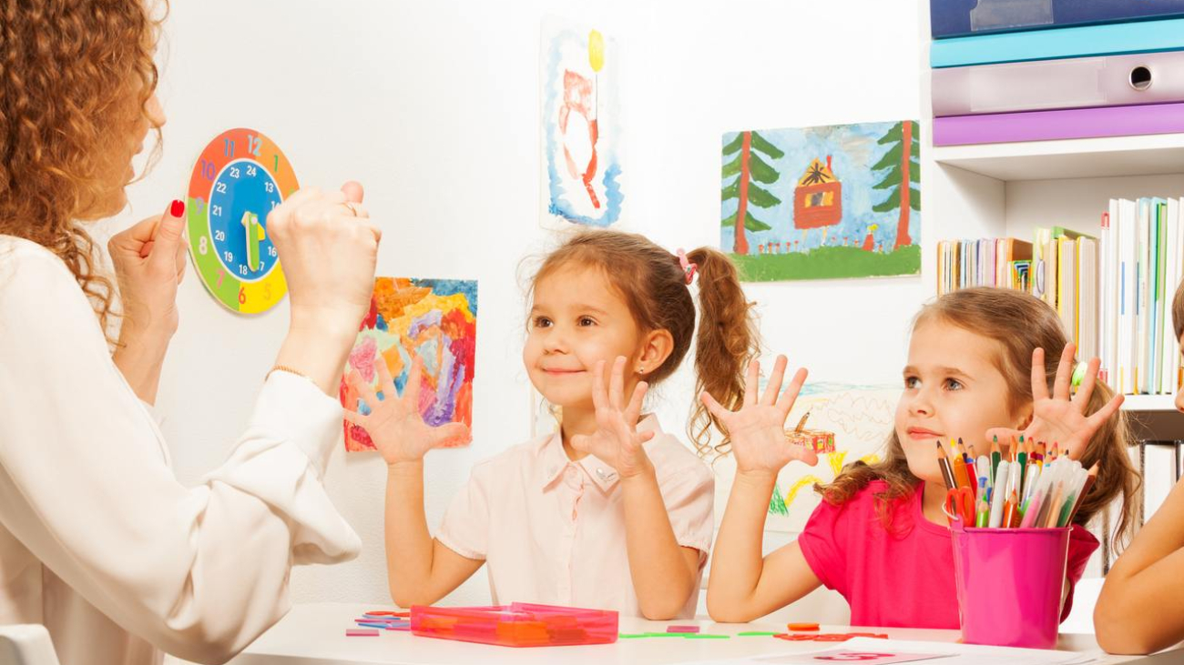 Two pupils, beautiful schoolgirls doing finger exercises as their teacher does in the classroom