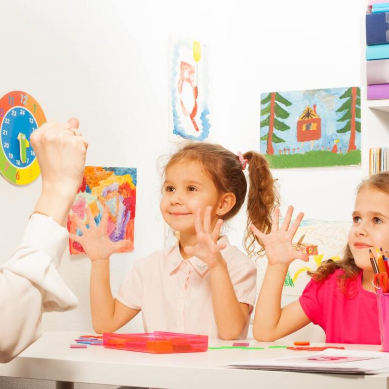 Two pupils, beautiful schoolgirls doing finger exercises as their teacher does in the classroom