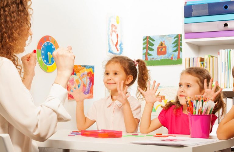 Two pupils, beautiful schoolgirls doing finger exercises as their teacher does in the classroom